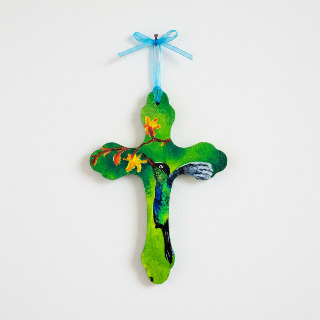 Hand-painted wooden wall cross featuring hummingbird feeding from flowers on green background with blue ribbon hanger