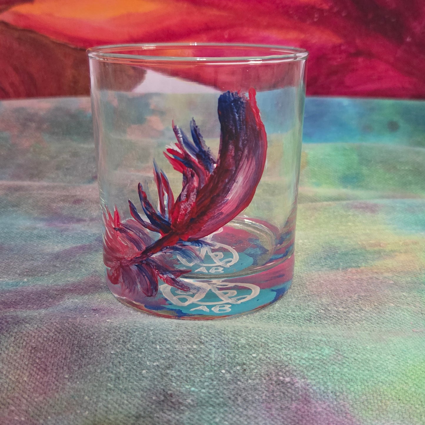 Hand-painted 11 oz short tumbler with a drifting cardinal feather in red, cobalt blue, and deep purple