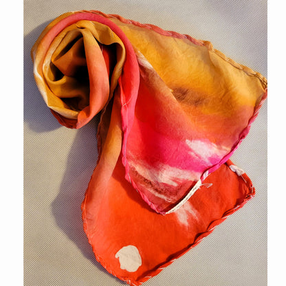 back of silk scarf swirled showing hand sewn rolled hem red and yellows with spots and feathery texture