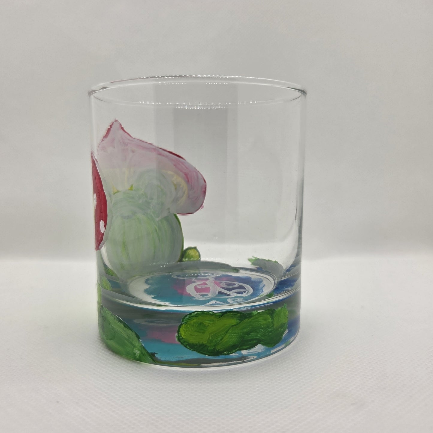 Hand-painted 11 oz highball glass featuring a whimsical frog sitting on a lily pad wearing a red mushroom hat with lily pad details wrapping around the glass.