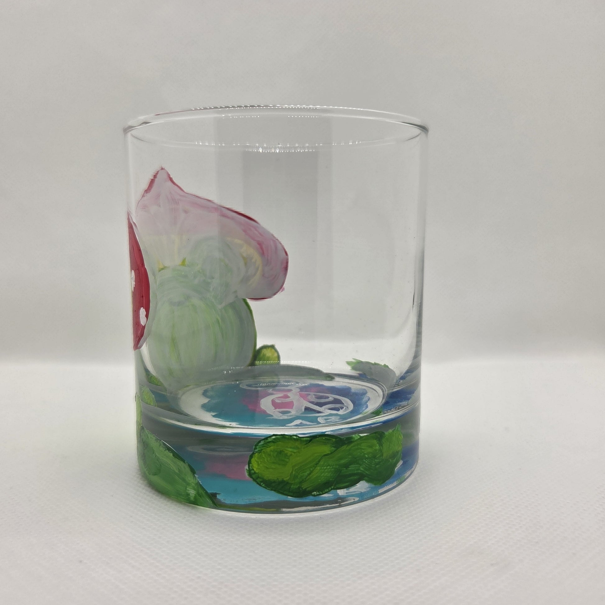 Hand-painted 11 oz highball glass featuring a whimsical frog sitting on a lily pad wearing a red mushroom hat with lily pad details wrapping around the glass.