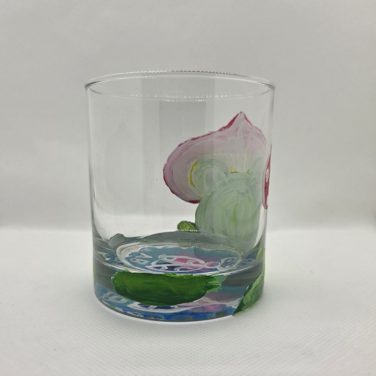 Hand-painted 11 oz highball glass featuring a whimsical frog sitting on a lily pad wearing a red mushroom hat with lily pad details wrapping around the glass.