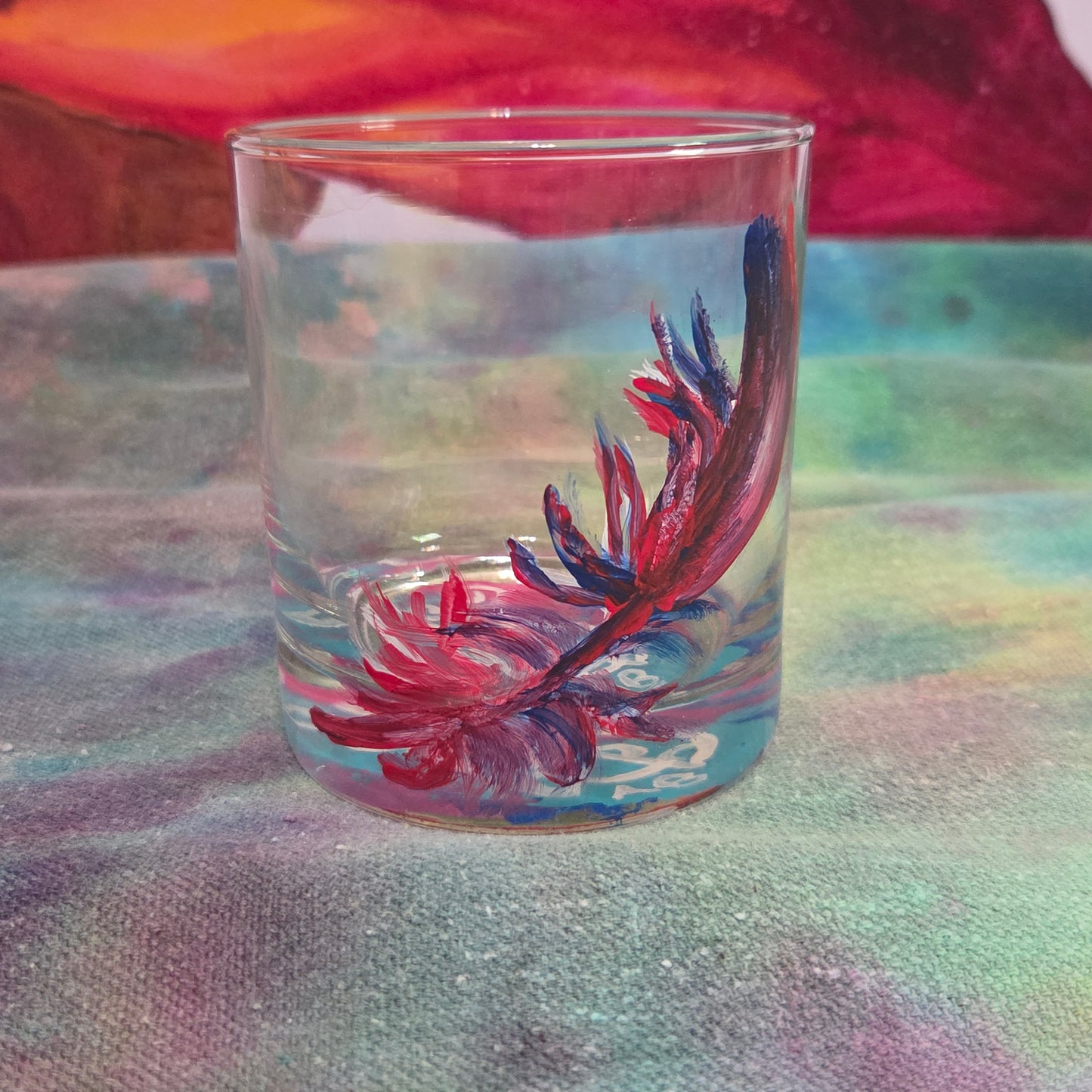 Hand-painted 11 oz short tumbler with a drifting cardinal feather in red, cobalt blue, and deep purple