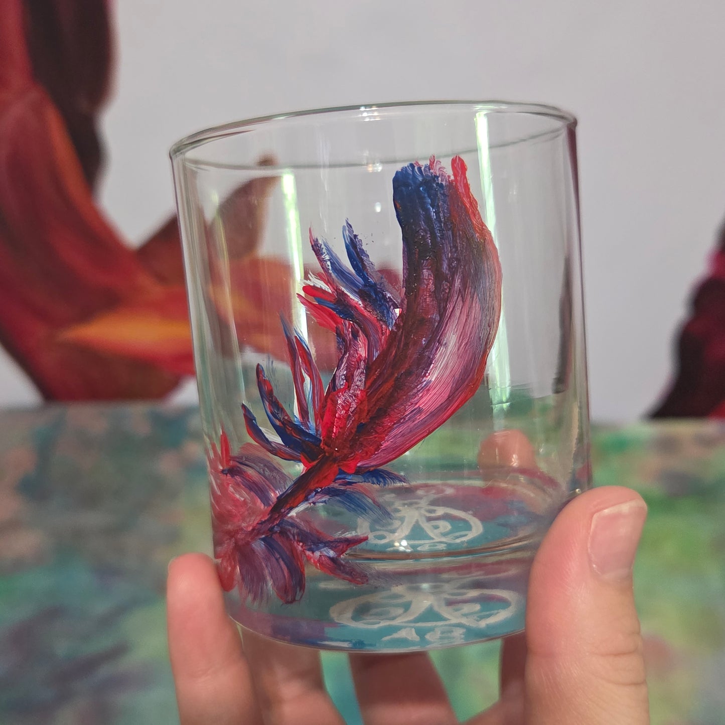 Hand-painted 11 oz short tumbler with a drifting cardinal feather in red, cobalt blue, and deep purple