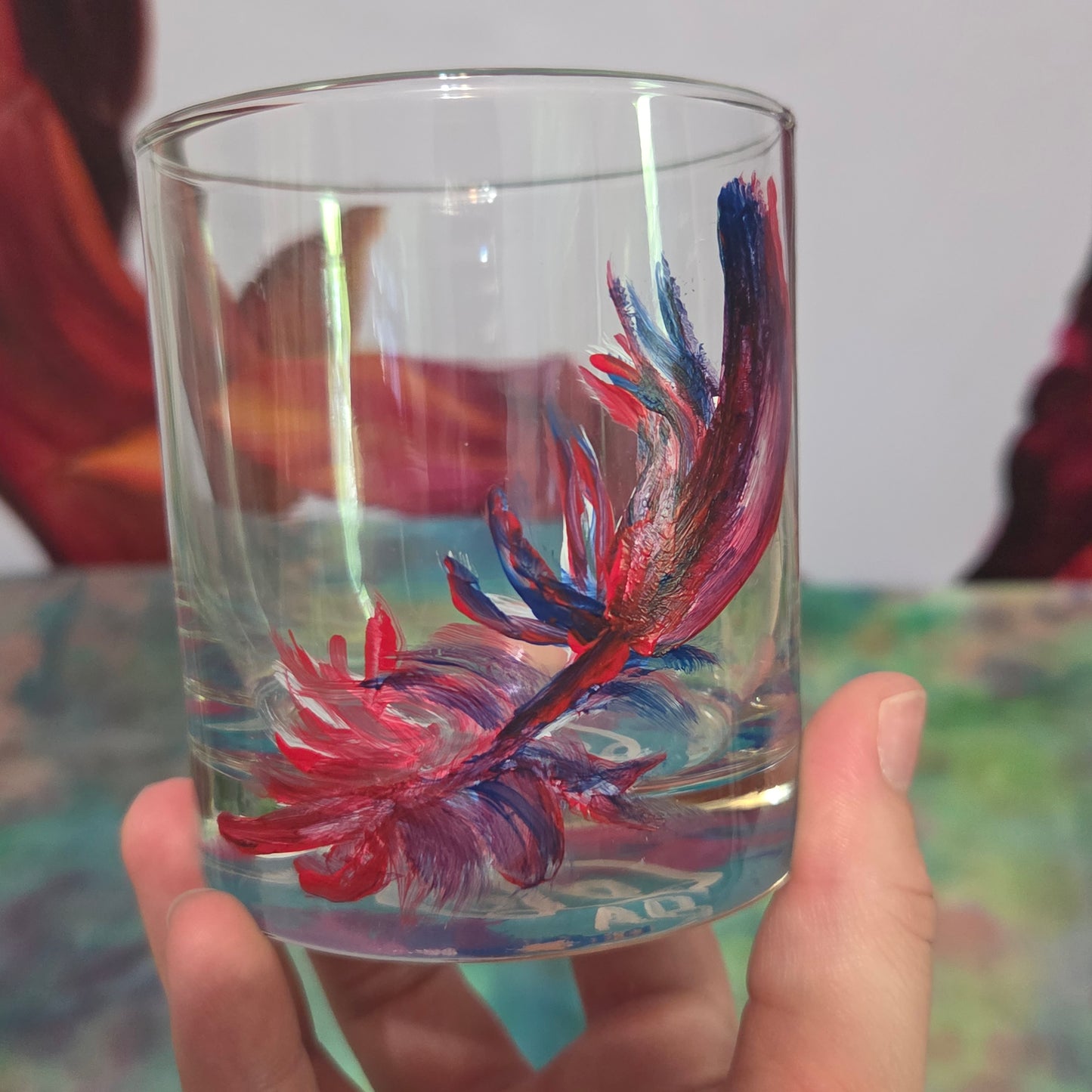 Hand-painted 11 oz short tumbler with a drifting cardinal feather in red, cobalt blue, and deep purple