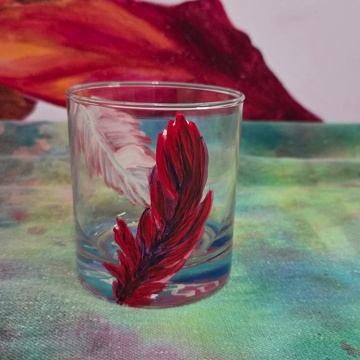 Hand-painted 11 oz short tumbler with two cardinal feathers in red, cobalt blue, and deep purple, one rising and one falling