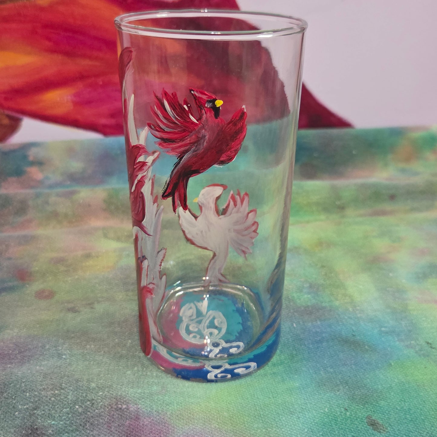 Hand-painted 16 oz tall tumbler with two flying cardinals surrounding a flowing feather