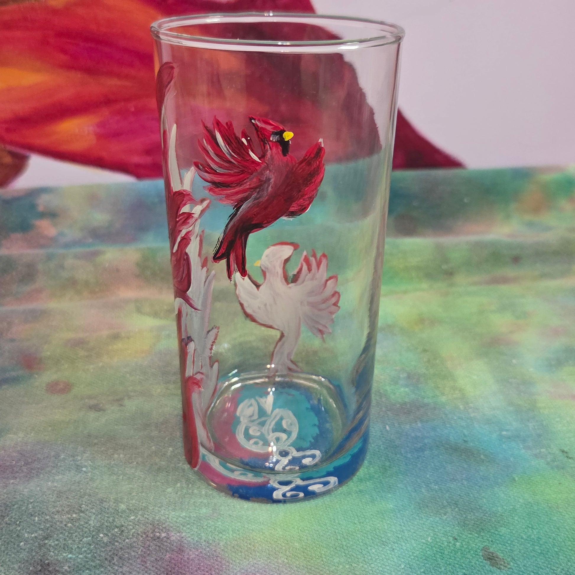 Hand-painted 16 oz tall tumbler with two flying cardinals surrounding a flowing feather