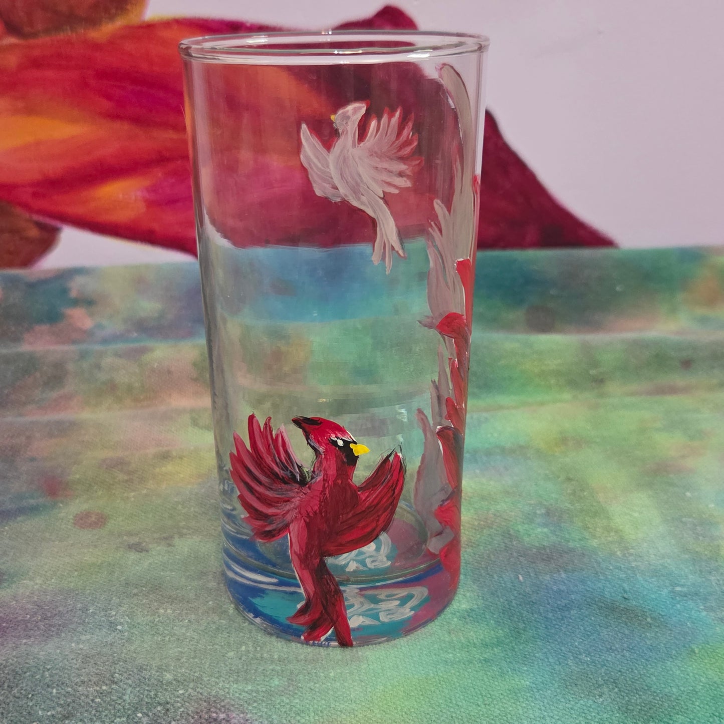 Hand-painted 16 oz tall tumbler with two flying cardinals surrounding a flowing feather
