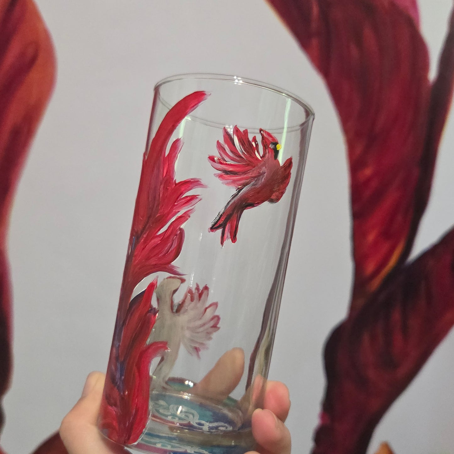 Hand-painted 16 oz tall tumbler with two flying cardinals surrounding a flowing feather