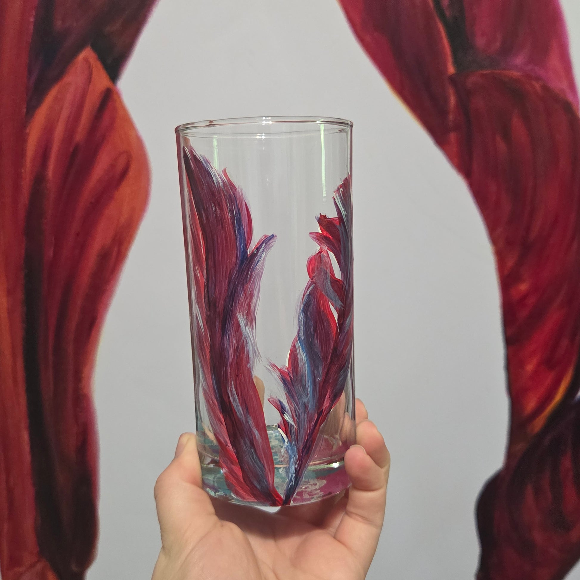 Hand-painted 16 oz tall tumbler with two flowing cardinal feathers in deep red, purple, cobalt blue, and white