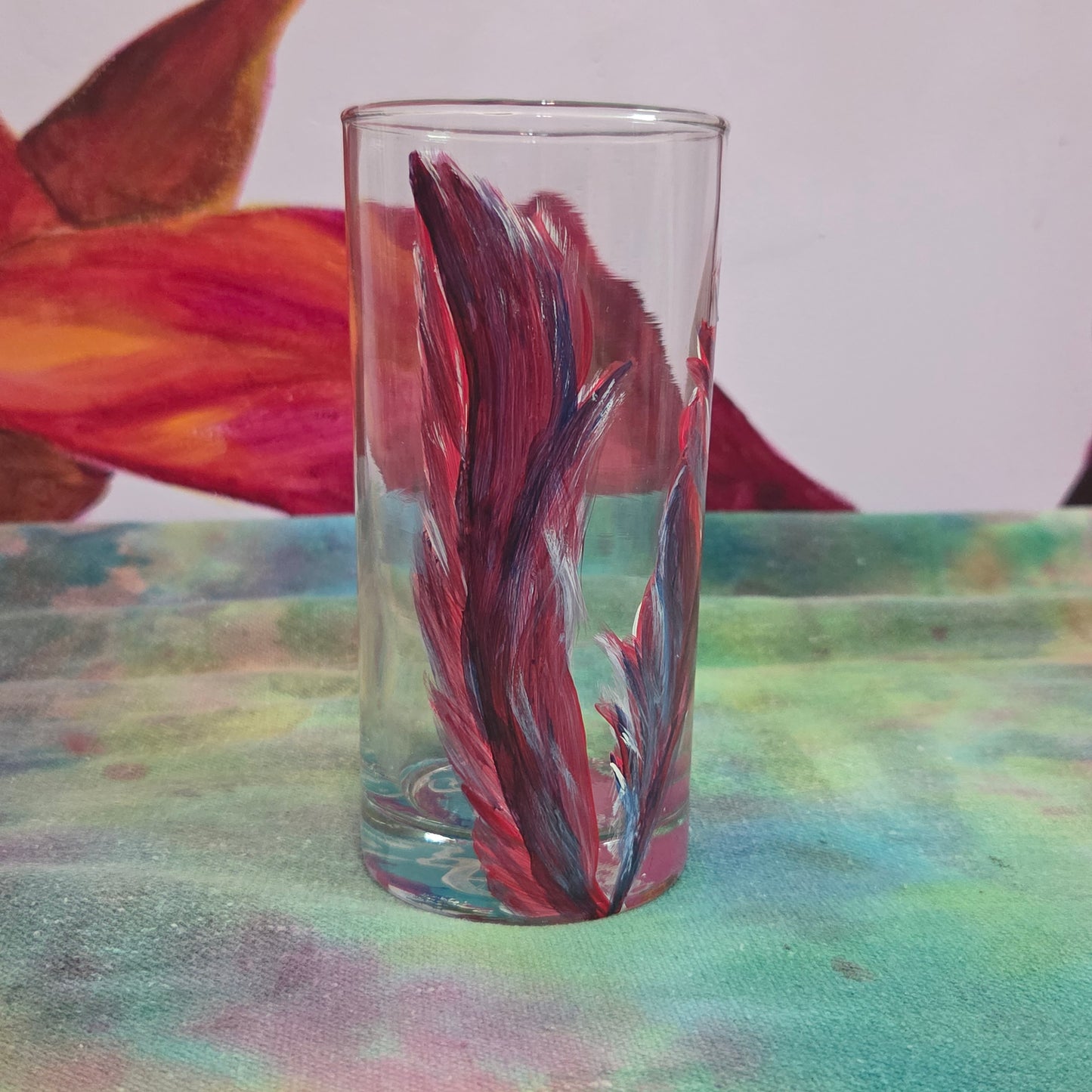 Hand-painted 16 oz tall tumbler with two flowing cardinal feathers in deep red, purple, cobalt blue, and white