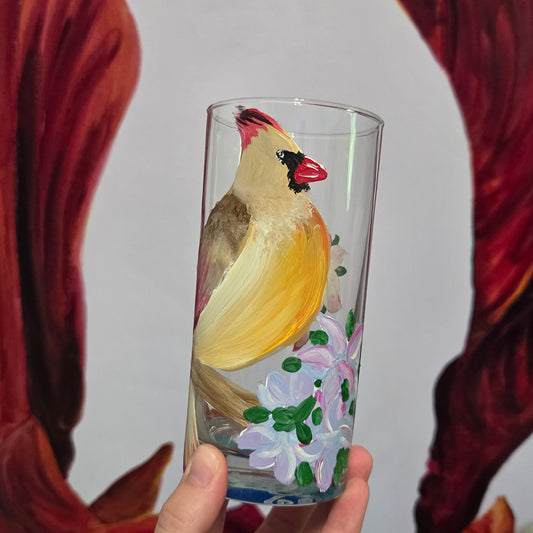 Hand-painted 16 oz tall tumbler with a female cardinal perched on a flowering branch surrounded by red, white, blue, and pink blossoms