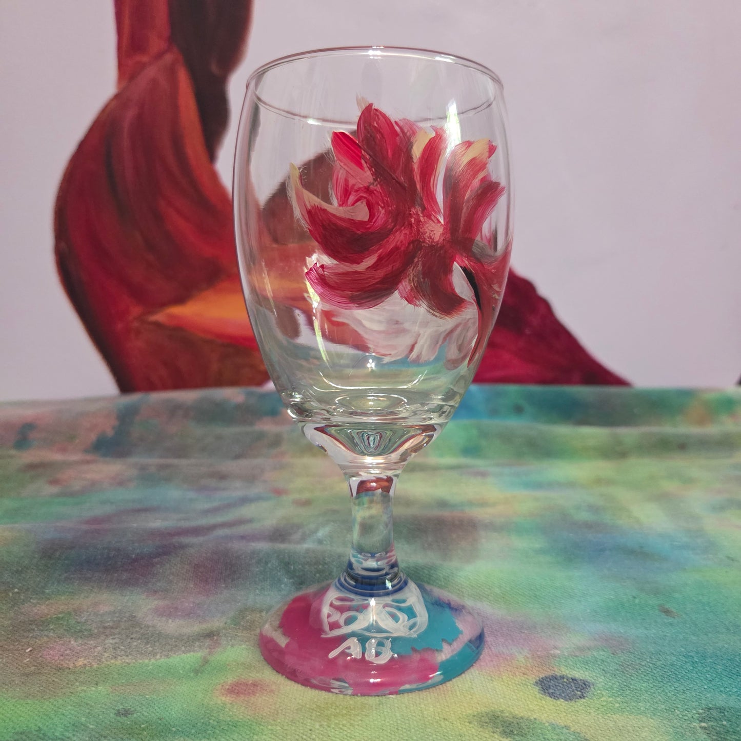 Hand-painted 16 oz goblet with a floating cardinal feather in red, orange, yellow, and subtle black shading