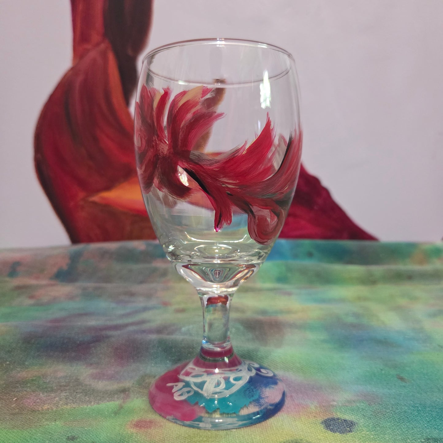 Hand-painted 16 oz goblet with a floating cardinal feather in red, orange, yellow, and subtle black shading