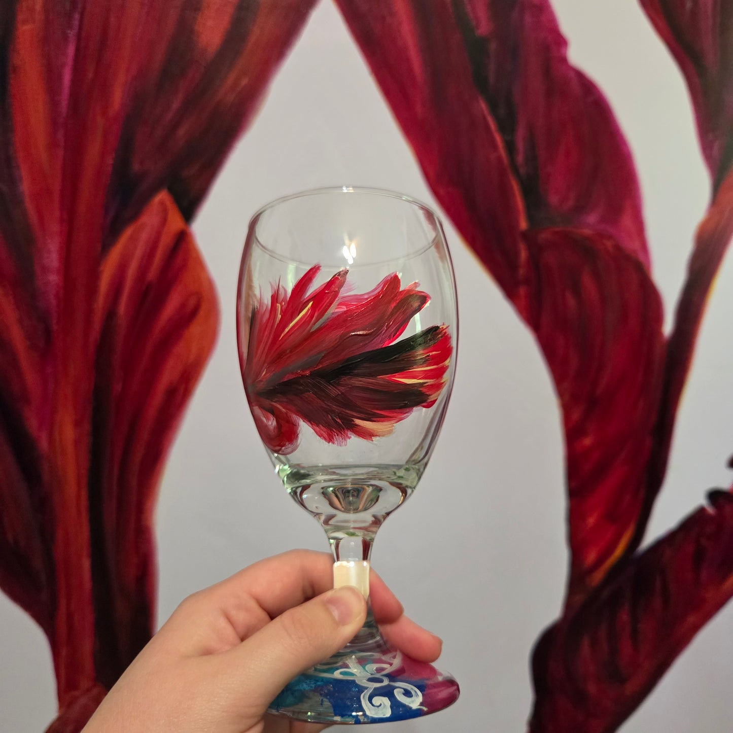 Hand-painted 16 oz goblet with a floating cardinal feather in red, orange, yellow, and subtle black shading