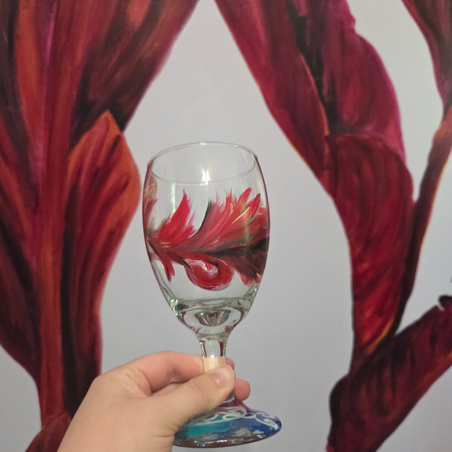 Hand-painted 16 oz goblet with a floating cardinal feather in red, orange, yellow, and subtle black shading