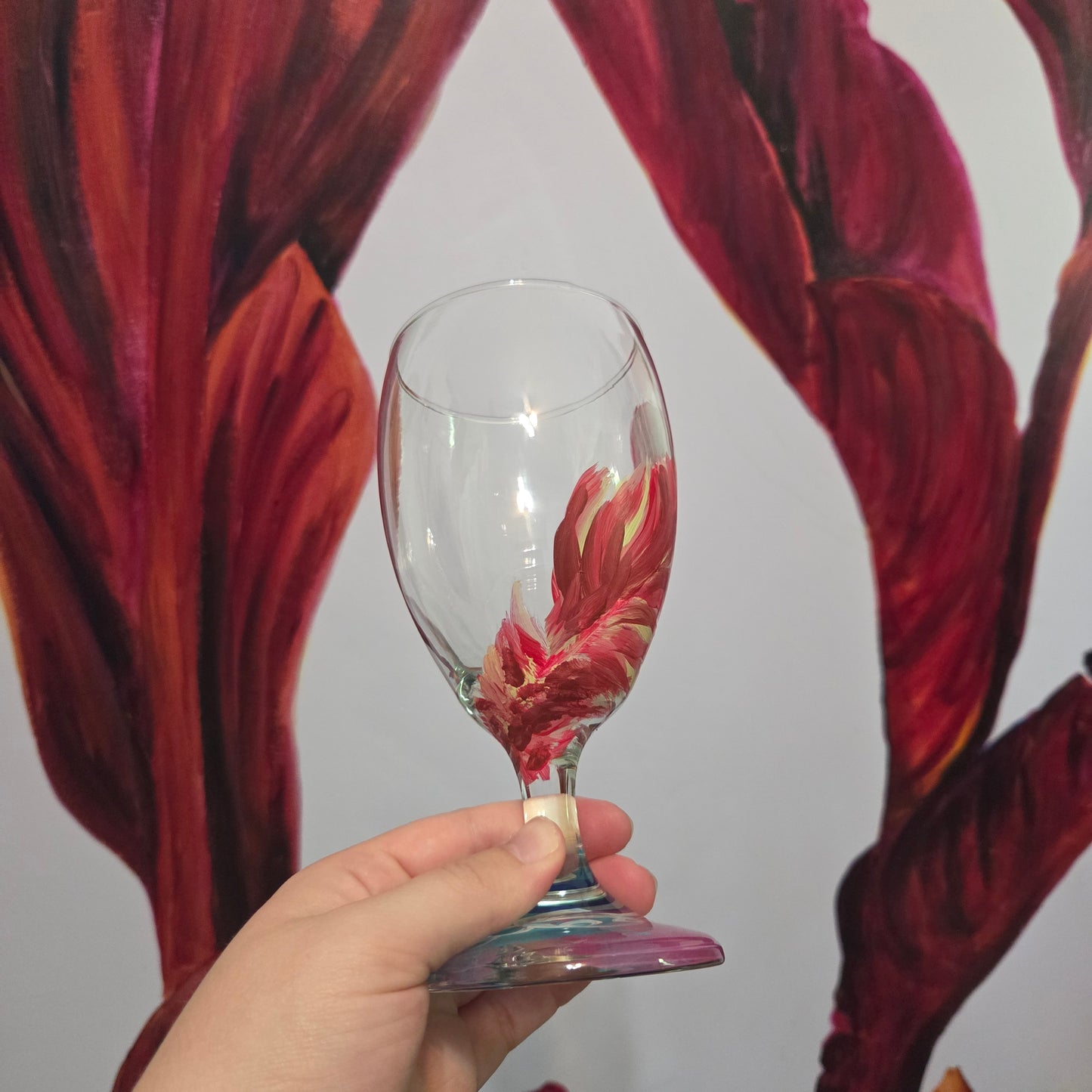 Hand-painted 16 oz glass with a graceful cardinal feather in brilliant red, orange, and golden yellow