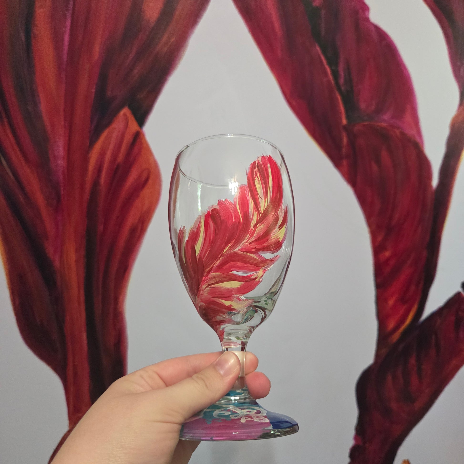 Hand-painted 16 oz glass with a graceful cardinal feather in brilliant red, orange, and golden yellow