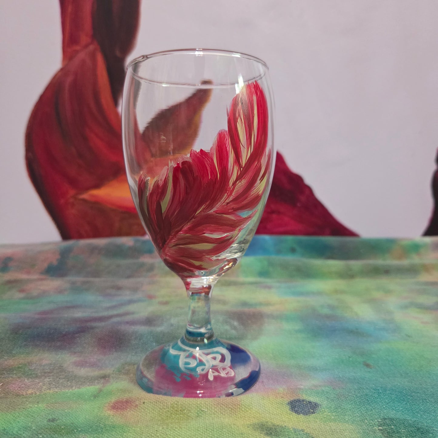 Hand-painted 16 oz glass with a graceful cardinal feather in brilliant red, orange, and golden yellow