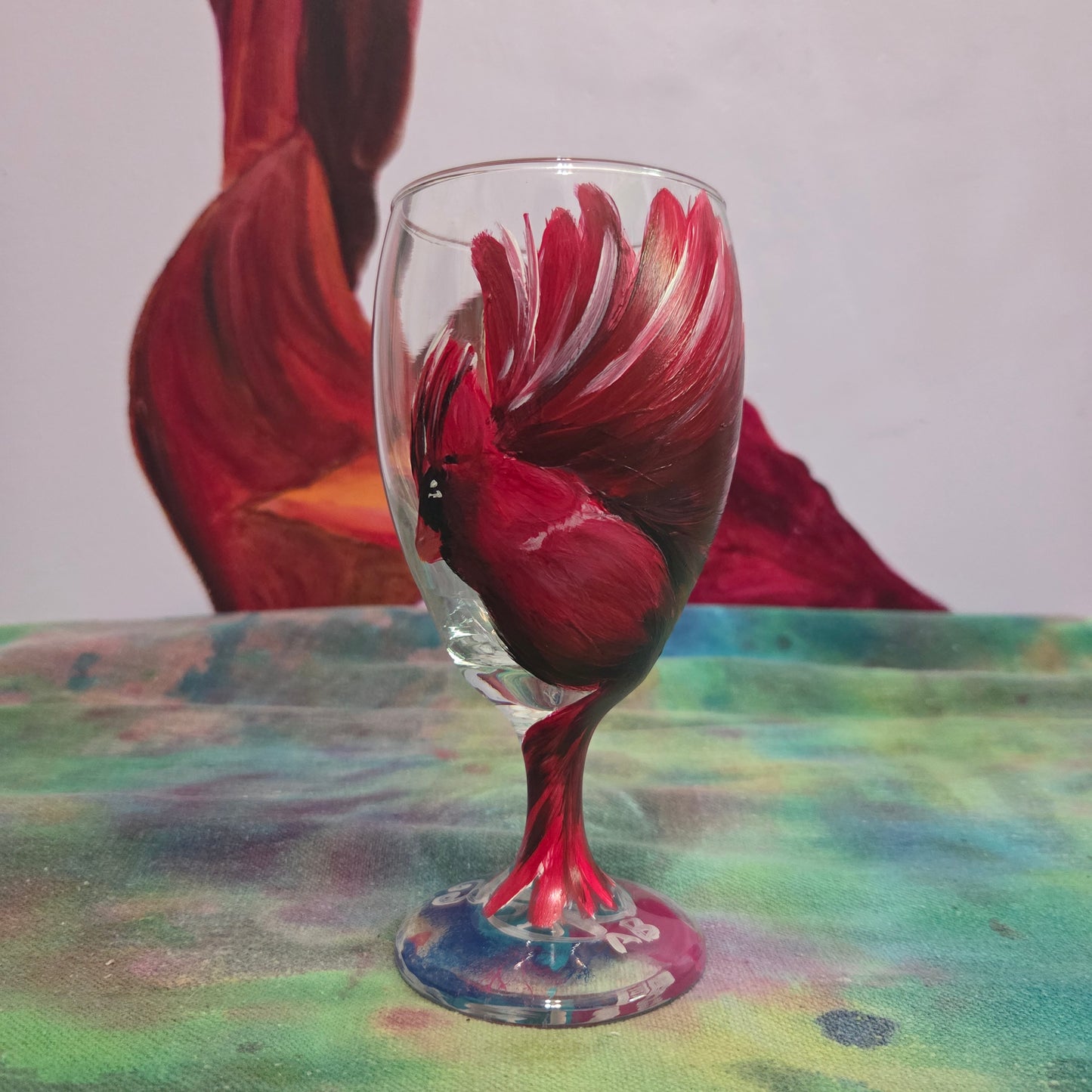 Hand-painted glass featuring a red male cardinal in flight looking down as he approaches his landing perch