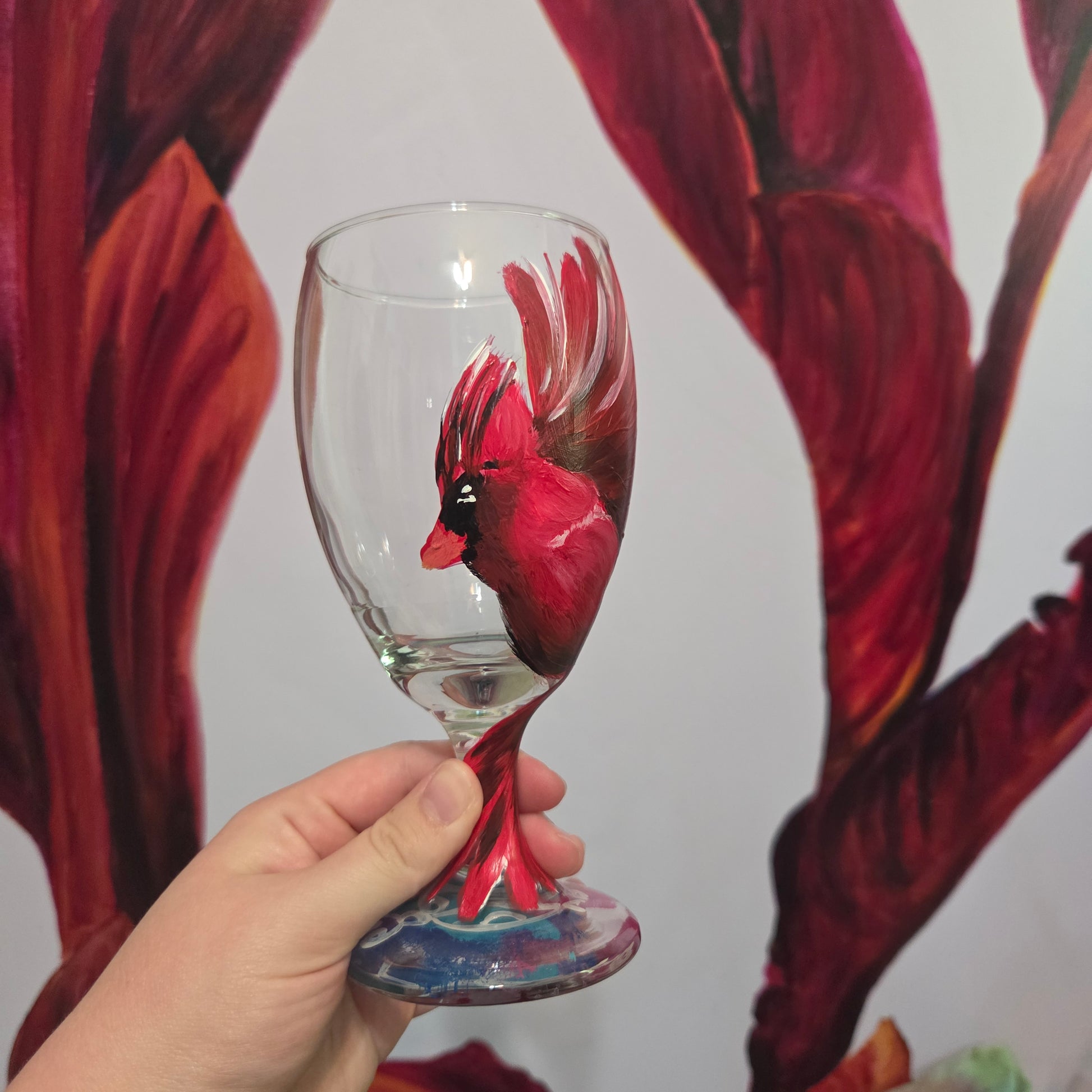 Hand-painted glass featuring a red male cardinal in flight looking down as he approaches his landing perch