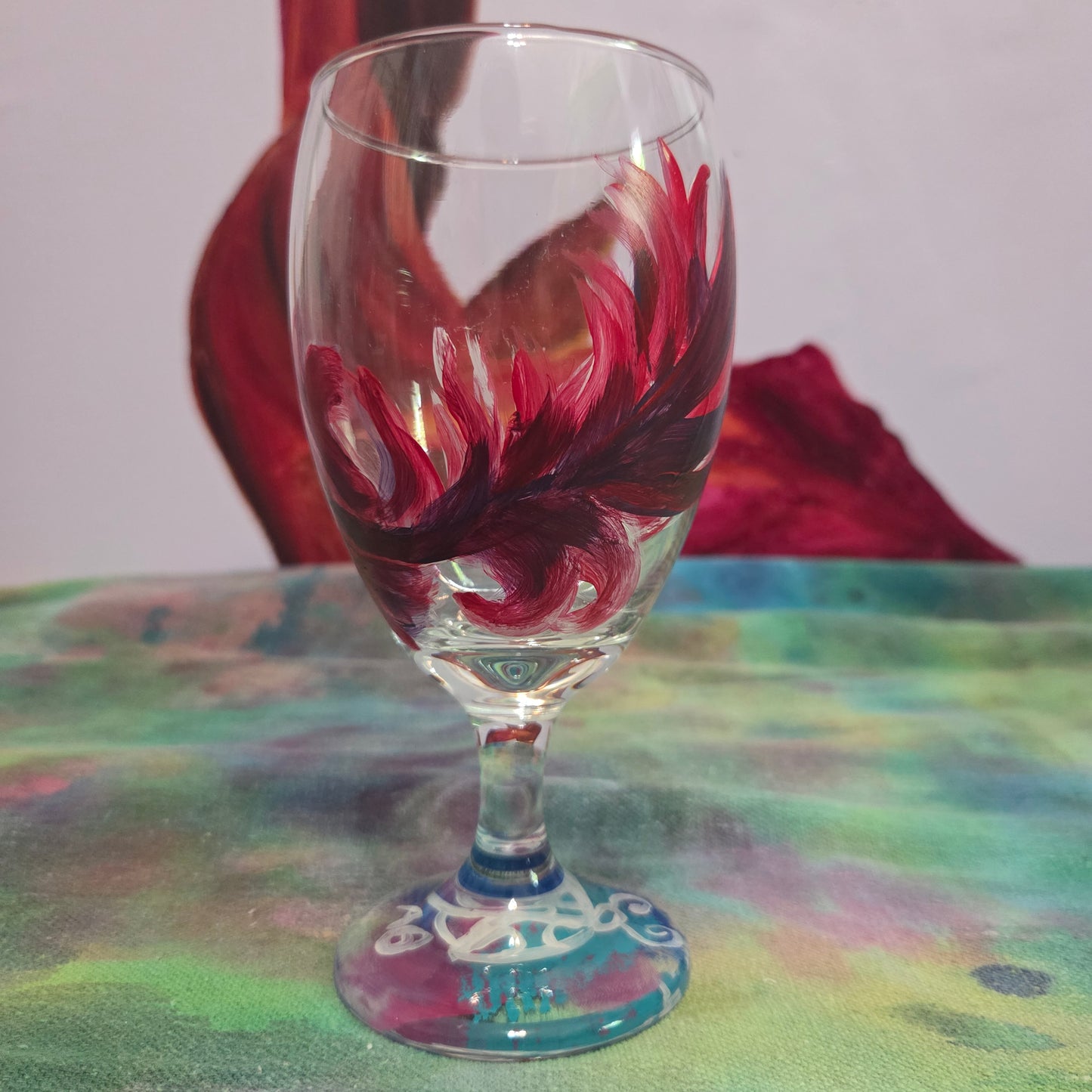 Hand-painted 16 oz goblet with a floating cardinal feather in bold red with black and subtle purple shadows