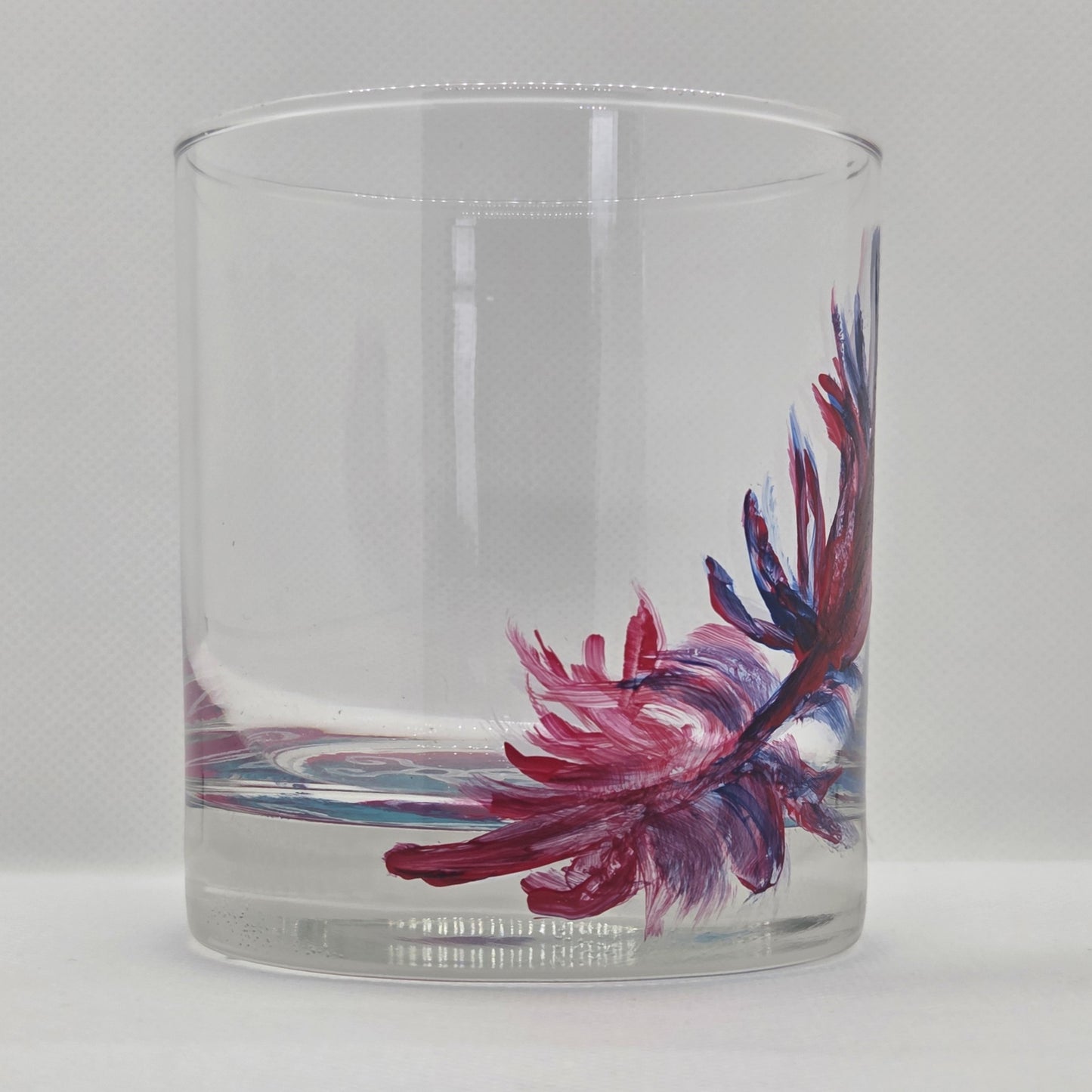 Hand-painted 11 oz short tumbler with a drifting cardinal feather in red, cobalt blue, and deep purple