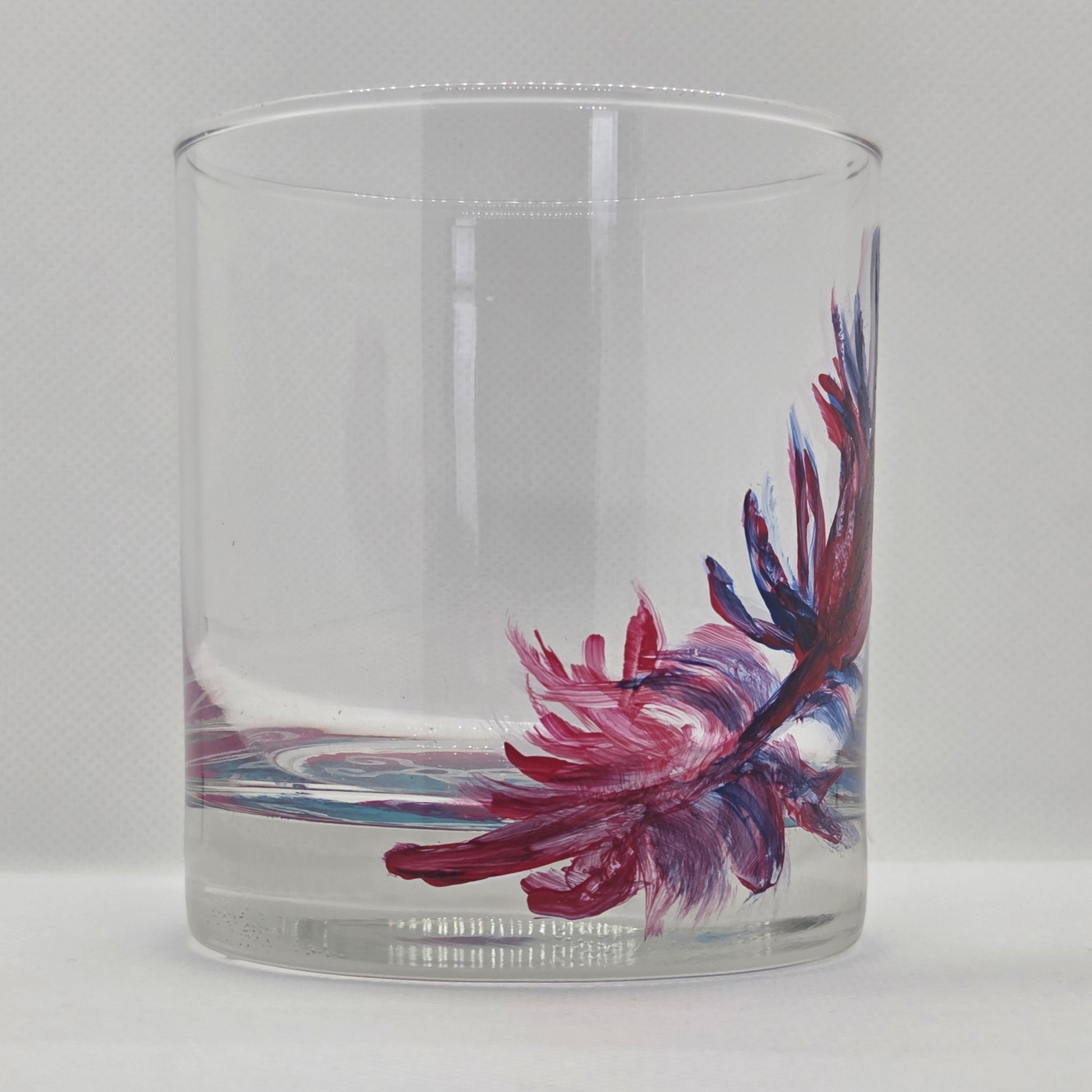 Hand-painted 11 oz short tumbler with a drifting cardinal feather in red, cobalt blue, and deep purple