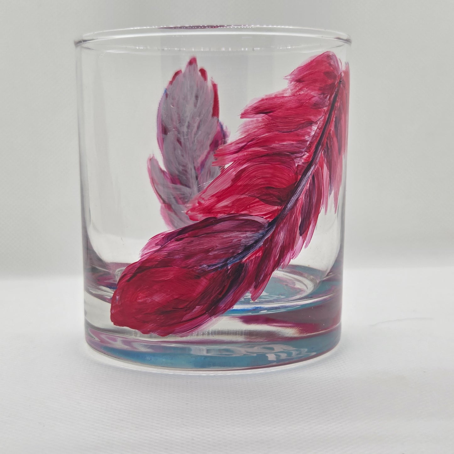 Hand-painted 11 oz short tumbler with two cardinal feathers in red, cobalt blue, and deep purple, one rising and one falling