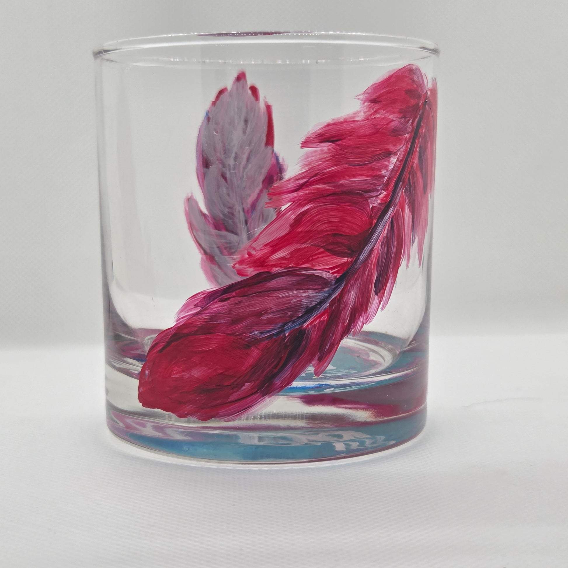 Hand-painted 11 oz short tumbler with two cardinal feathers in red, cobalt blue, and deep purple, one rising and one falling