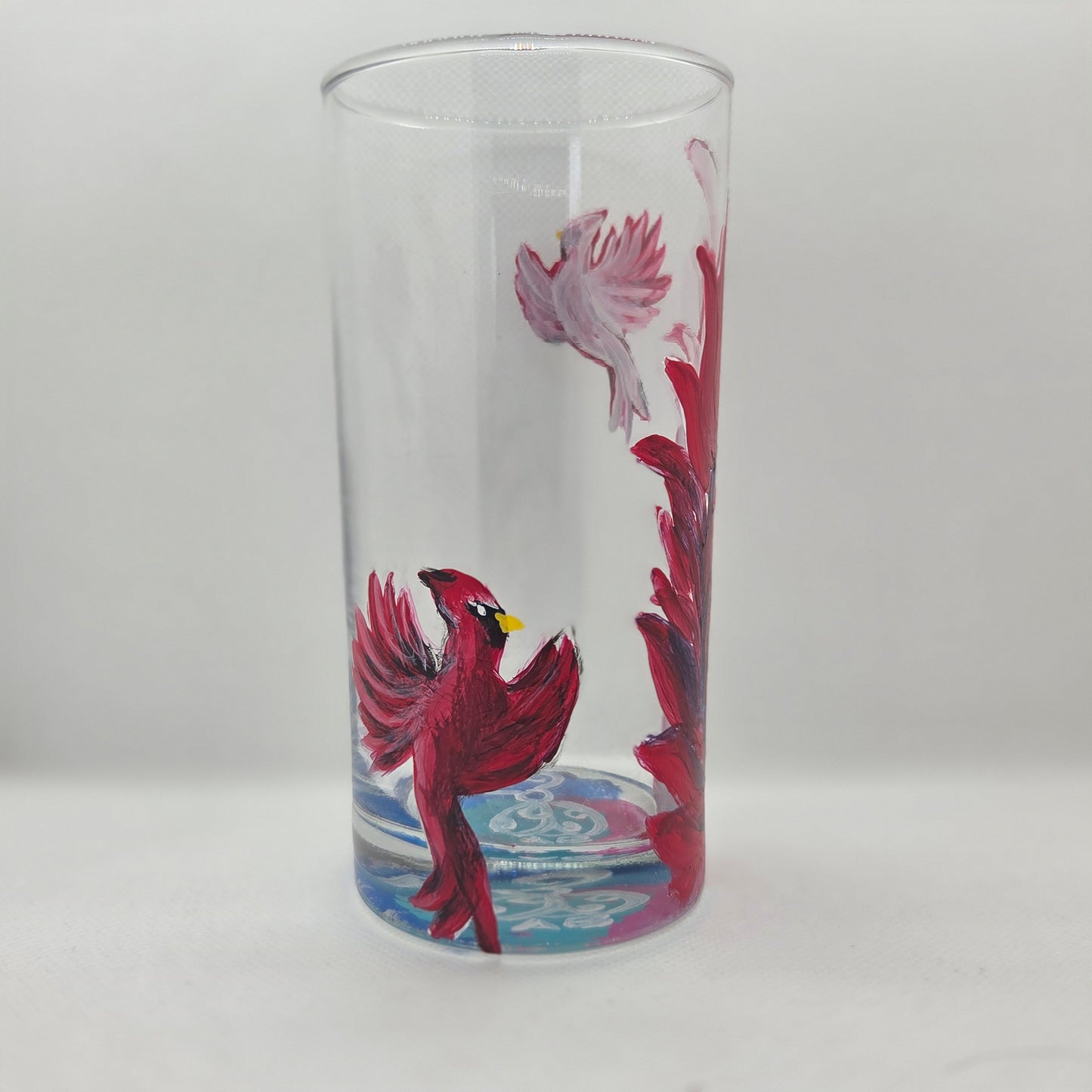 Hand-painted 16 oz tall tumbler with two flying cardinals surrounding a flowing feather