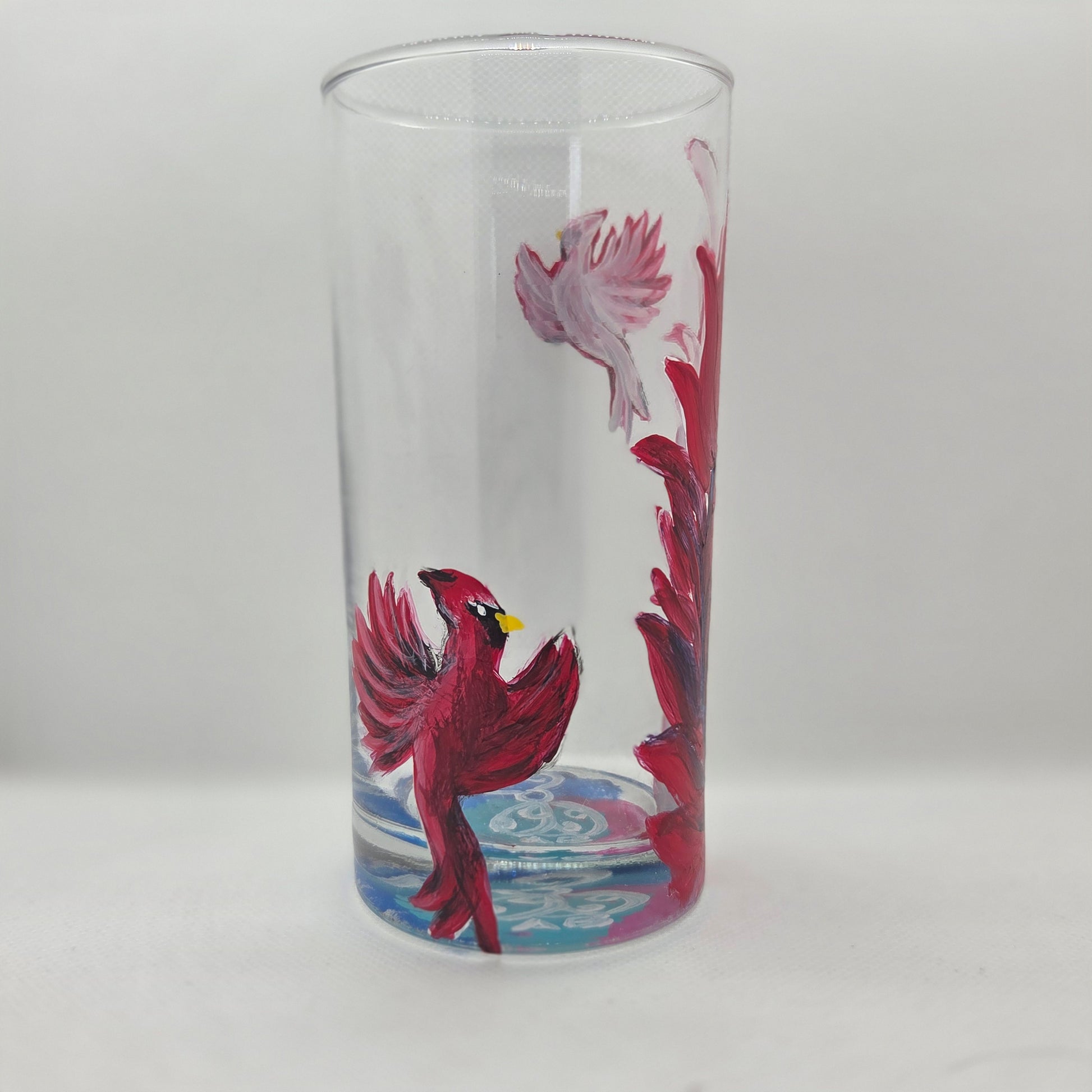 Hand-painted 16 oz tall tumbler with two flying cardinals surrounding a flowing feather