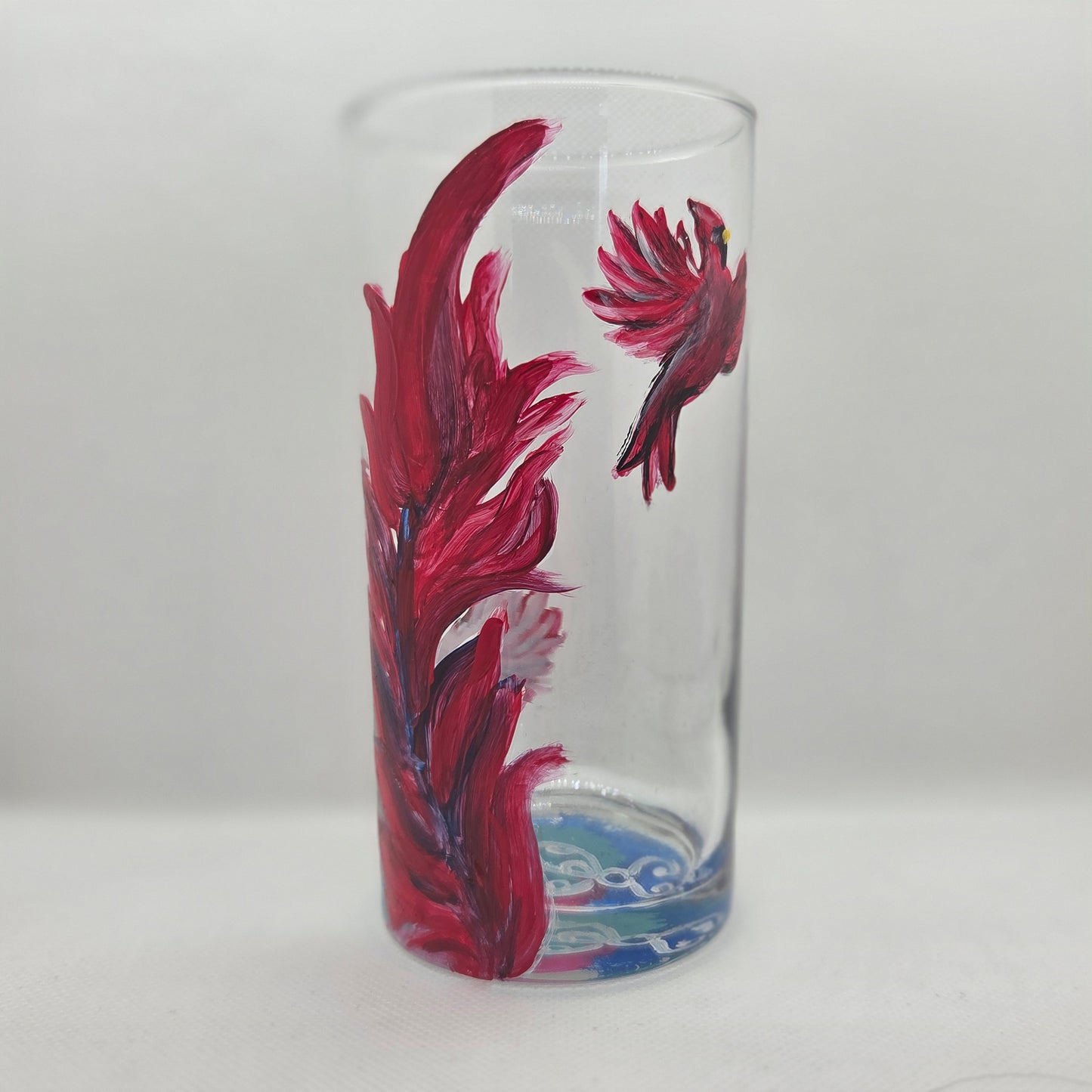 Hand-painted 16 oz tall tumbler with two flying cardinals surrounding a flowing feather