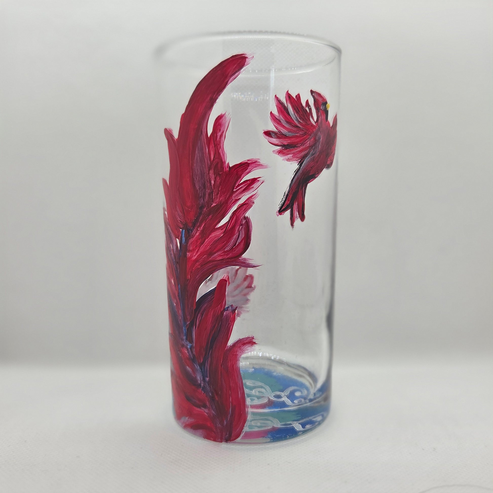 Hand-painted 16 oz tall tumbler with two flying cardinals surrounding a flowing feather