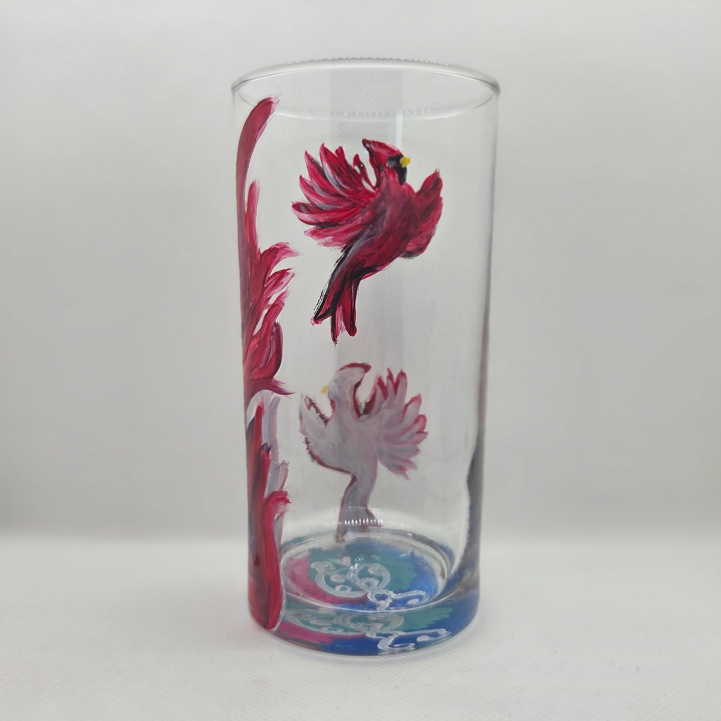 Hand-painted 16 oz tall tumbler with two flying cardinals surrounding a flowing feather