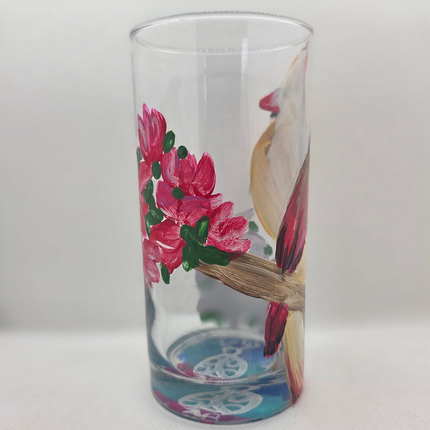 Hand-painted 16 oz tall tumbler with a female cardinal perched on a flowering branch surrounded by red, white, blue, and pink blossoms