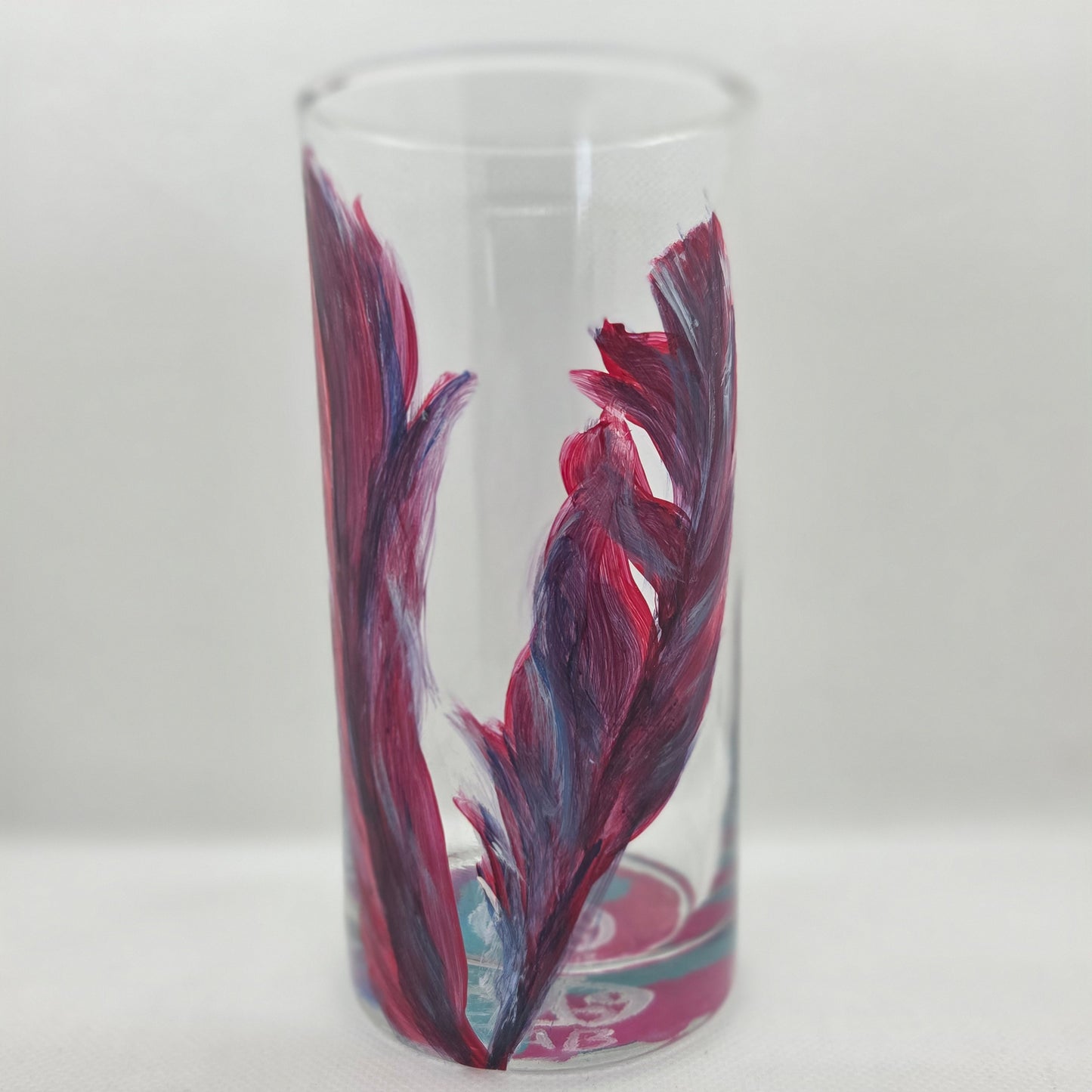 Hand-painted 16 oz tall tumbler with two flowing cardinal feathers in deep red, purple, cobalt blue, and white