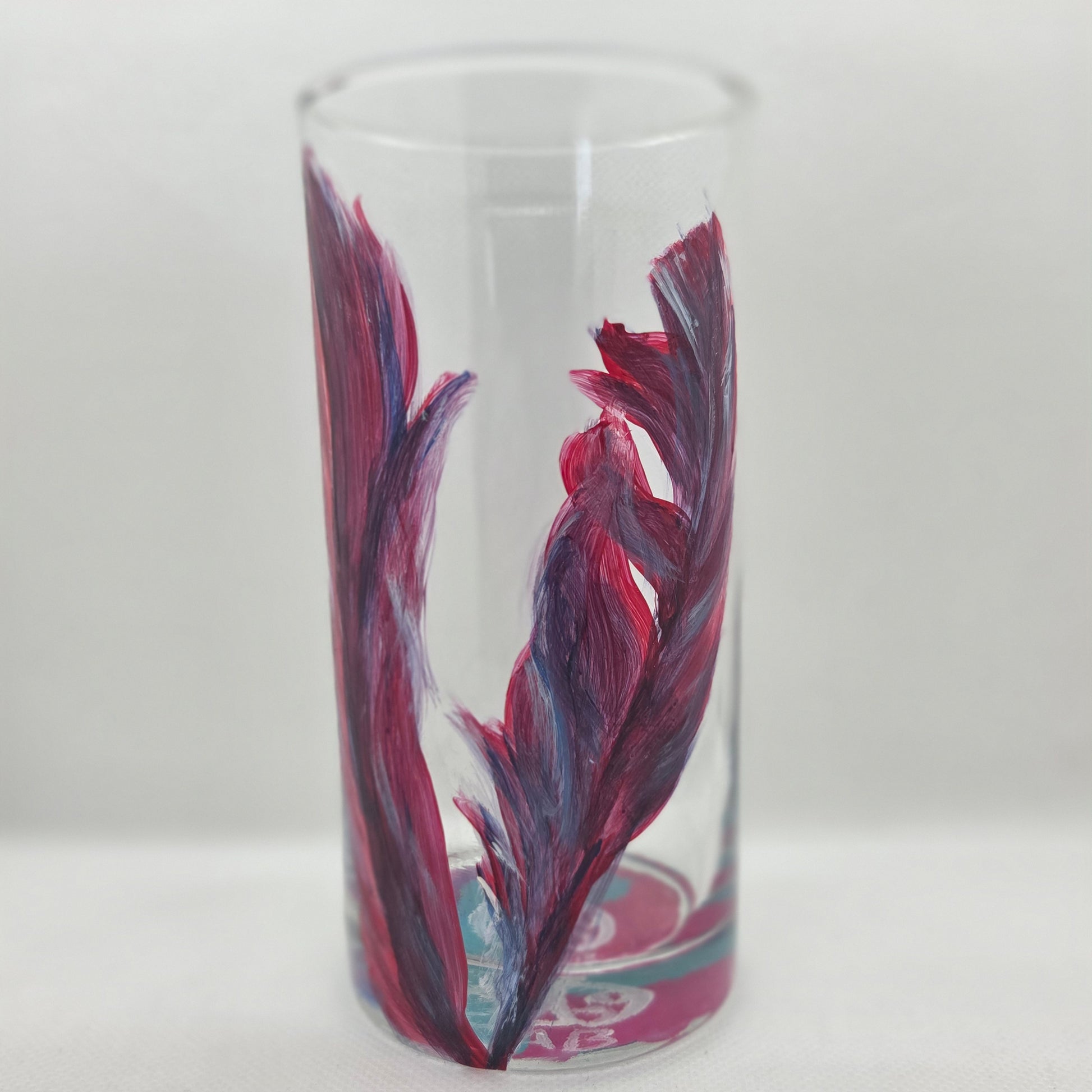 Hand-painted 16 oz tall tumbler with two flowing cardinal feathers in deep red, purple, cobalt blue, and white