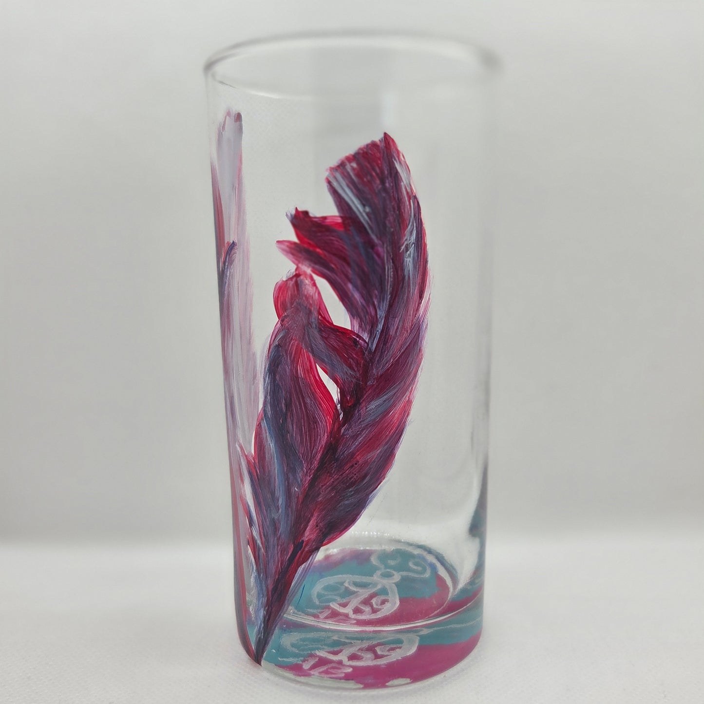 Hand-painted 16 oz tall tumbler with two flowing cardinal feathers in deep red, purple, cobalt blue, and white