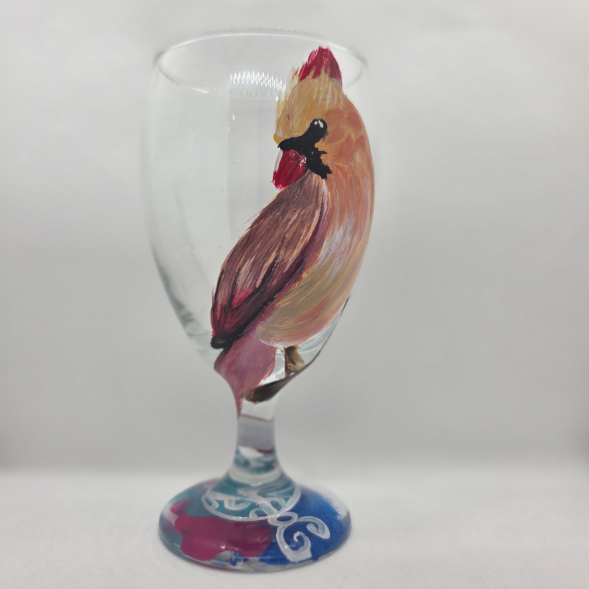 Hand-painted 16 oz goblet with a female cardinal looking over her shoulder, perched on a branch with peach-pink coloring