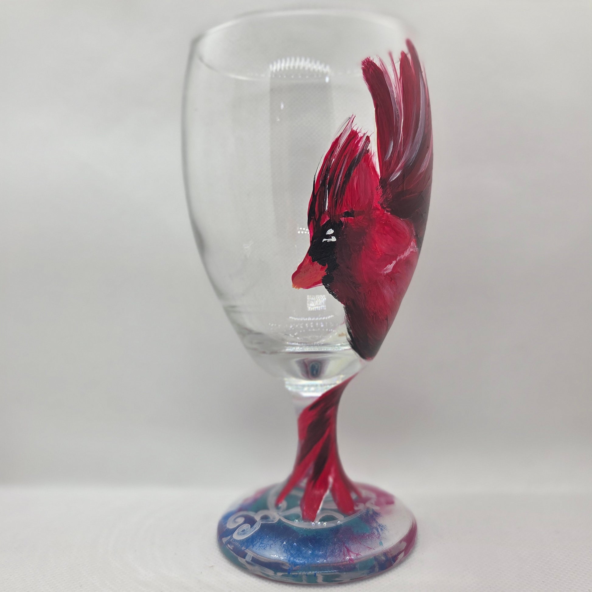 Hand-painted glass featuring a red male cardinal in flight looking down as he approaches his landing perch