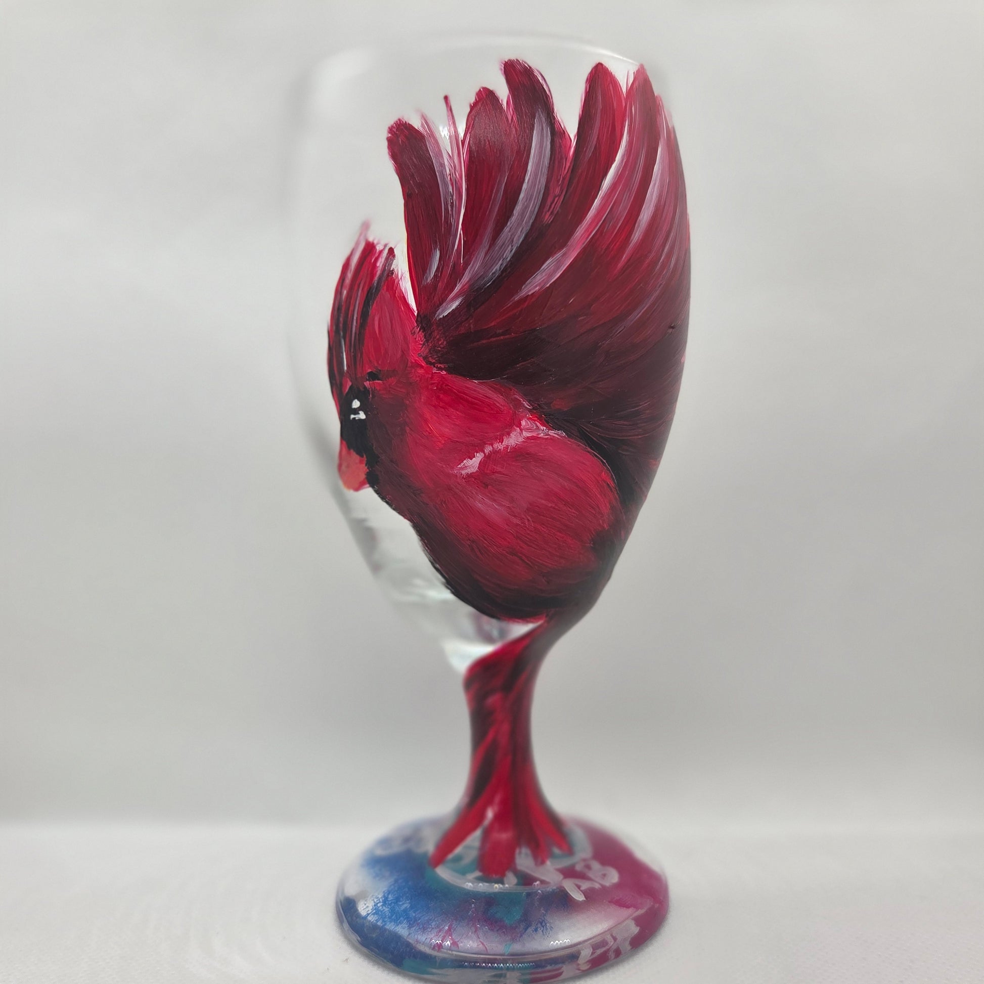 Hand-painted glass featuring a red male cardinal in flight looking down as he approaches his landing perch
