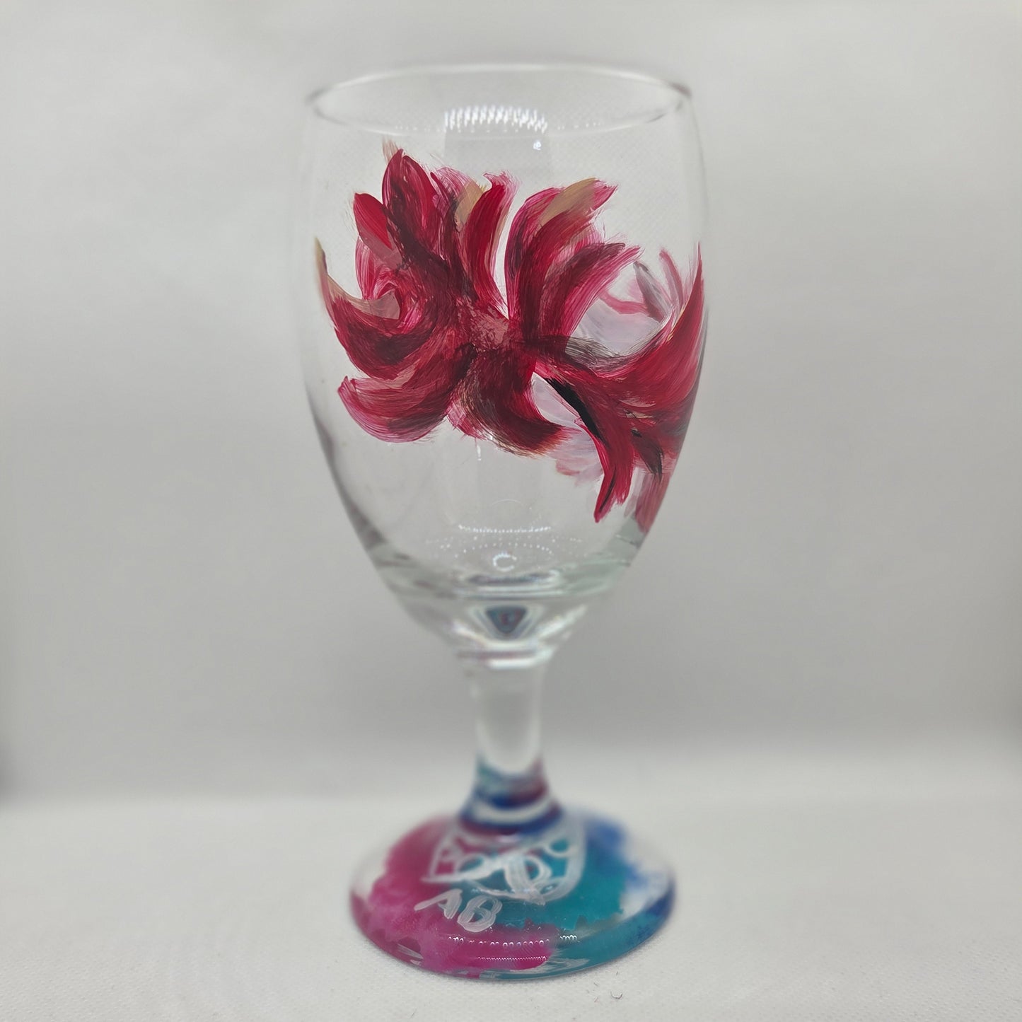 Hand-painted 16 oz goblet with a floating cardinal feather in red, orange, yellow, and subtle black shading