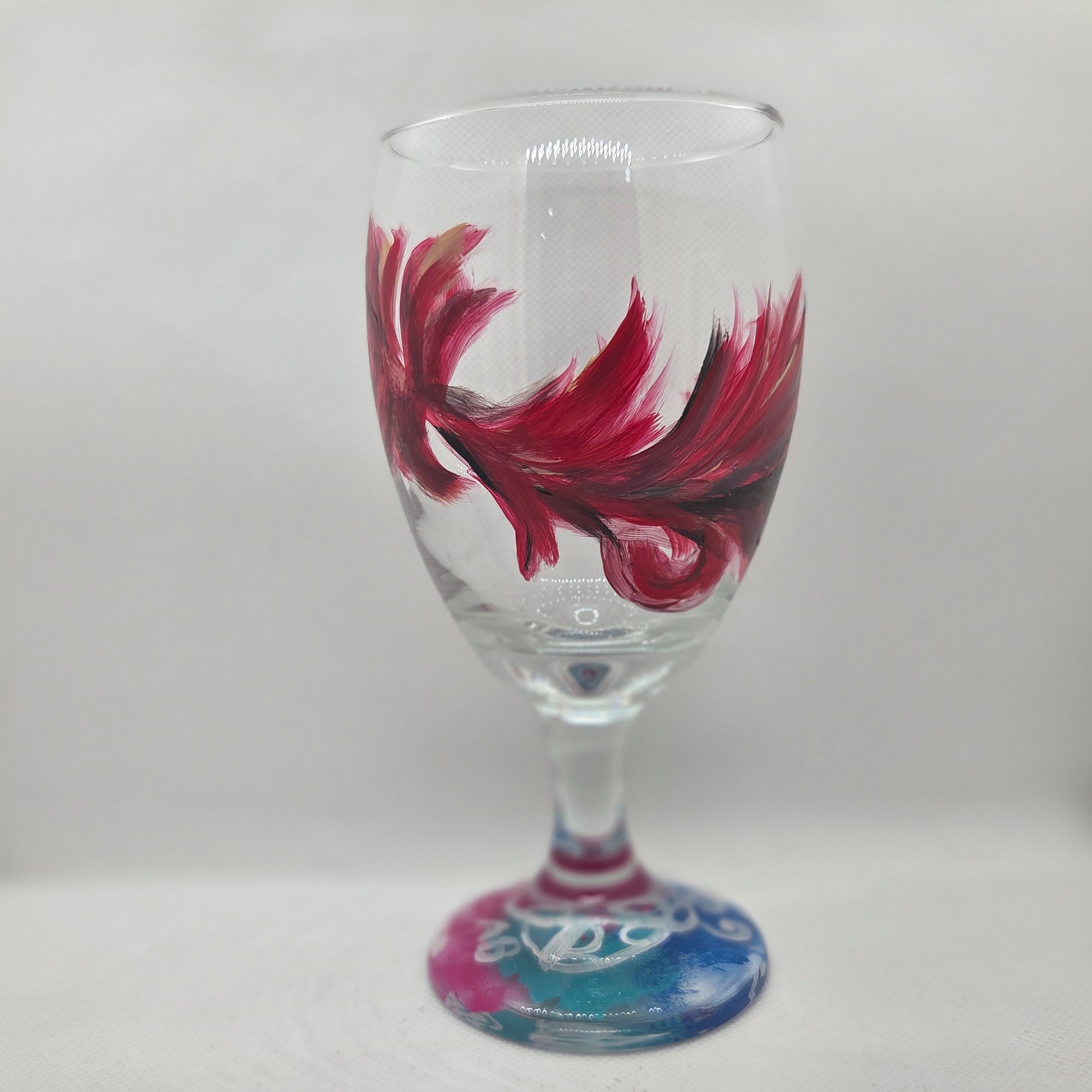 Hand-painted 16 oz goblet with a floating cardinal feather in red, orange, yellow, and subtle black shading