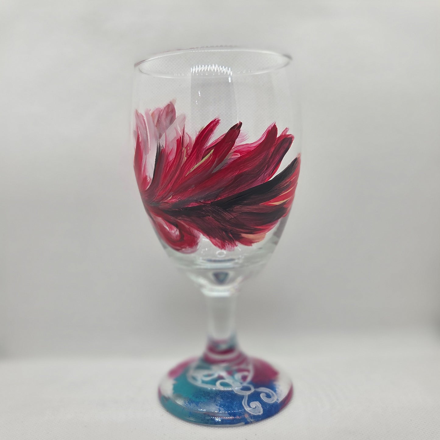 Hand-painted 16 oz goblet with a floating cardinal feather in red, orange, yellow, and subtle black shading