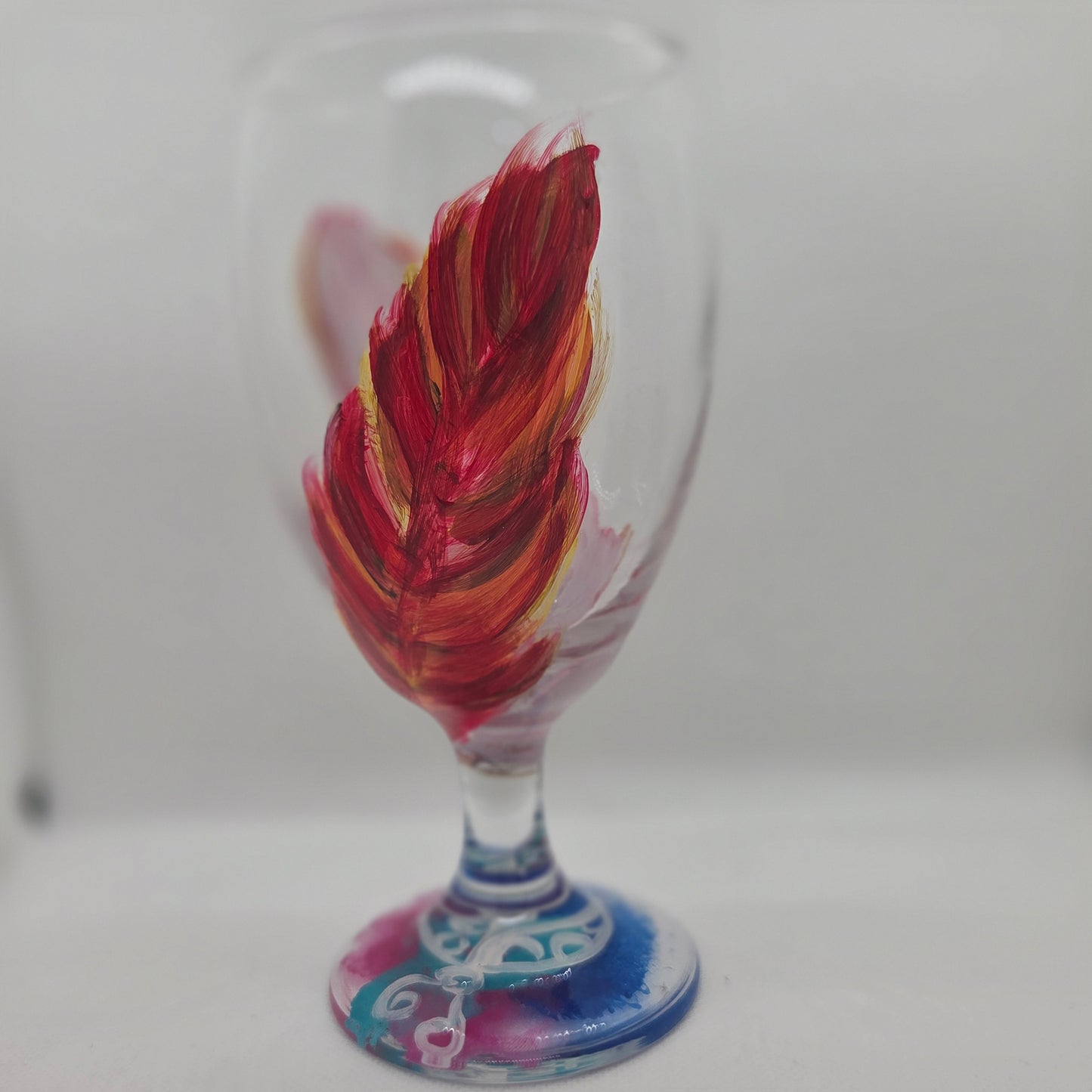 Hand-painted 16 oz goblet with two upright cardinal feathers in red, orange, and golden yellow