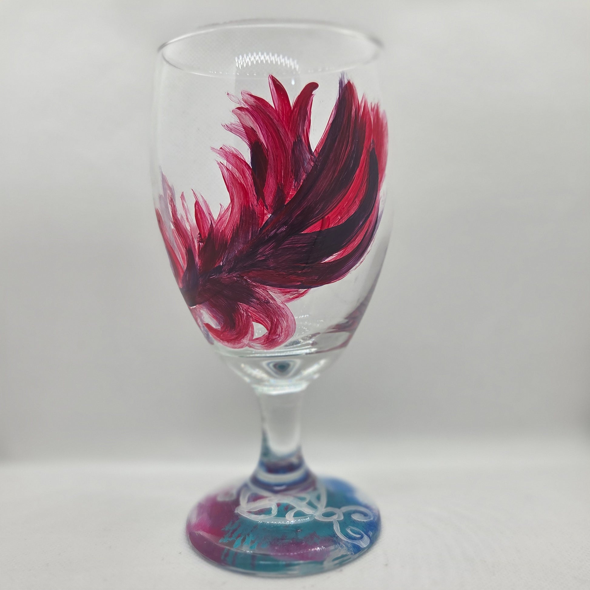 Hand-painted 16 oz goblet with a floating cardinal feather in bold red with black and subtle purple shadows