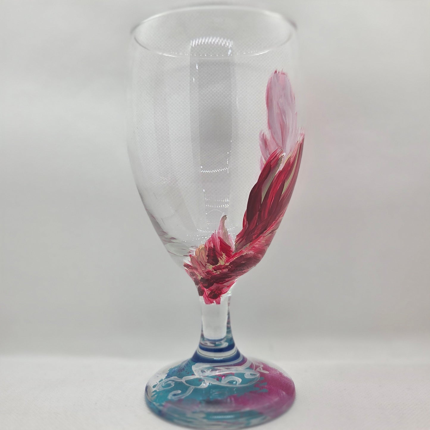 Hand-painted 16 oz glass with a graceful cardinal feather in brilliant red, orange, and golden yellow