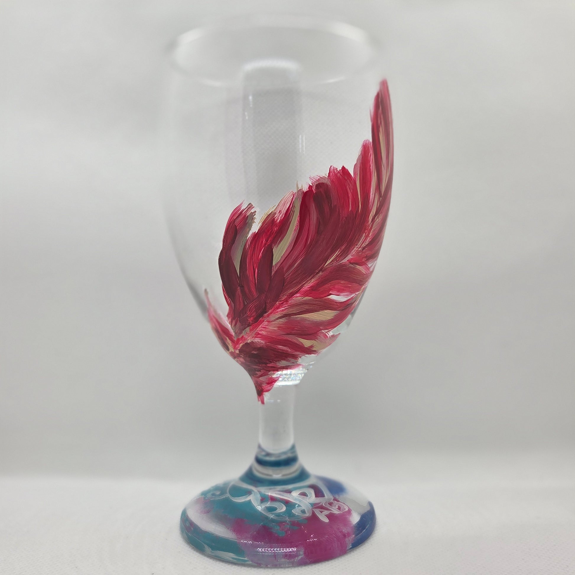 Hand-painted 16 oz glass with a graceful cardinal feather in brilliant red, orange, and golden yellow
